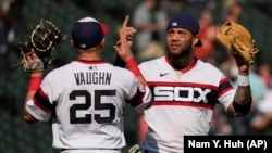 El tercera base cubano Yoán Moncada junto al primera base Andrew Vaughn celebran la victoria de los Medias Blancas sobre los Atléticos de Oakland, en Chicago, este domingo, 27 de agosto de 2023. (AP Foto/Nam Y. Huh)