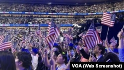 Asistentes a la Convención Nacional Demócrata 2024 ondean banderas de EEUU en el United Center de Chicago, el 22 de agosto de 2024.