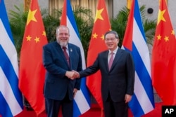 En esta fotografía publicada por la agencia de noticias Xinhua, el primer ministro cubano Manuel Marrero Cruz, a la izquierda, es recibido por su homólogo chino Li Qiang. (Zhai Jianlan/Xinhua vía AP)