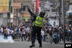 Un policía antidisturbios utiliza gases lacrimógenos contra manifestantes durante una protesta de opositores al gobierno del presidente venezolano Nicolás Maduro en el barrio de Catia, en Caracas, el 29 de julio de 2024. Yuri CORTEZ / AFP