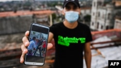 El joven Rolando Remedios muestra una foto en su celular de su arresto durante las protestas del 11 de julio. (YAMIL LAGE / AFP)