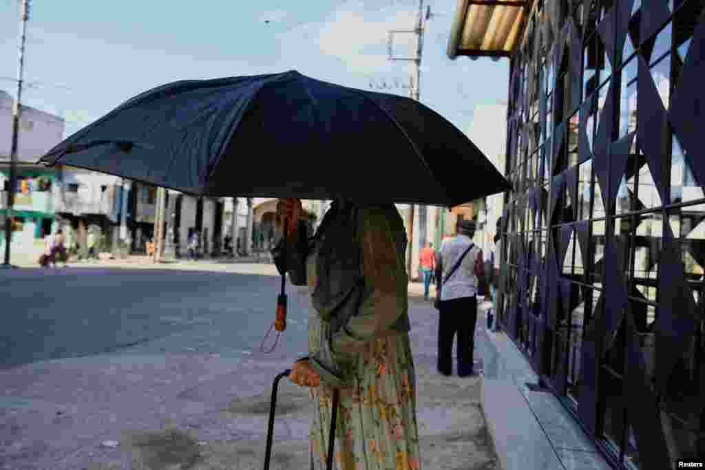 Una mujer se cubre del sol bajo un paraguas después de salir de una tienda, en La Habana, Cuba, 4 de septiembre de 2024. REUTERS/Norlys Pérez