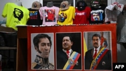 Camisetas y gorras en apoyo al gobierno venezolano junto a retratos del Libertador Simón Bolívar, el fallecido presidente venezolano Hugo Chávez y el candidato presidencial venezolano Nicolás Maduro en un taller en Maracaibo. Foto de Raul ARBOLEDA / AFP