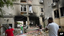 Israelíes en Ashkelon inspeccionan edificio atacado por Hamás. Imagen del 9 de octubre de 2023. (AP Photo/Erik Marmor).