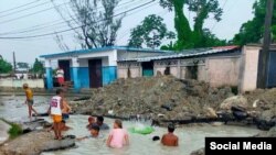 Niños se bañan en una zanja creada por el salidero de una tubería averiada en una calle de La Habana. (Facebook/Blanca Díaz Hernández)